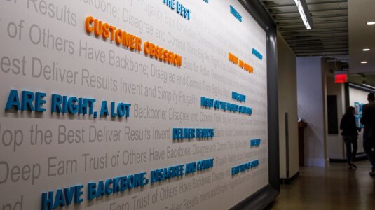 A wall in an Amazon office is covered with the different Leadership Principles